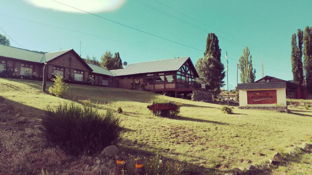 una casa sentada en la cima de un campo de hierba en El Hostal del Rio en Aluminé