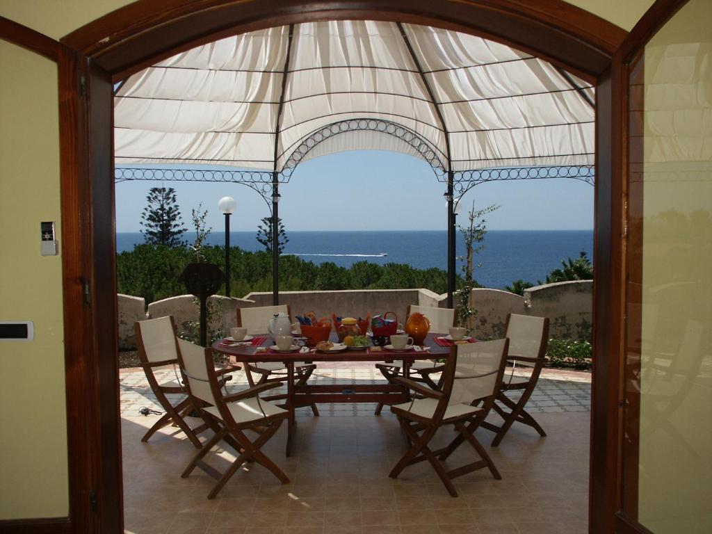 einen Esstisch mit Stühlen und Meerblick in der Unterkunft Terrazza sul Plemmirio in Syrakus