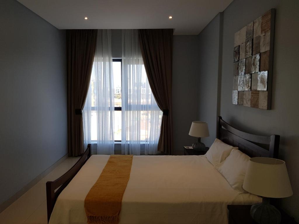 a bedroom with a large bed and a window at Apartments at Itowers, CBD, Gaborone in Gaborone