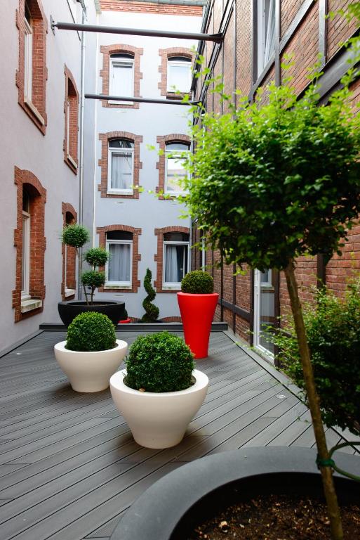 a courtyard with four pots of plants and a building at Saint Georges Hotel &amp; Spa in Chalon-sur-Saône