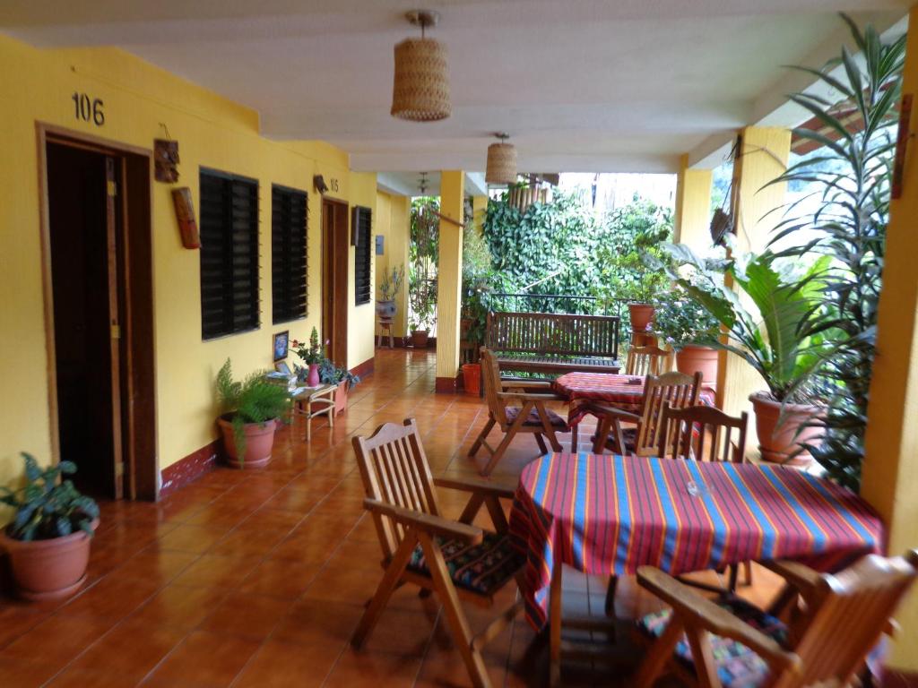 un restaurante con mesas, sillas y plantas en Hotel Encuentro del Viajero en Panajachel