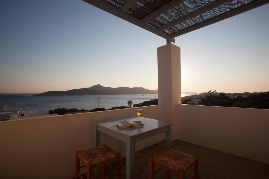 een tafel met een glas wijn op een balkon bij Oliaros seaside complex in Agios Georgios