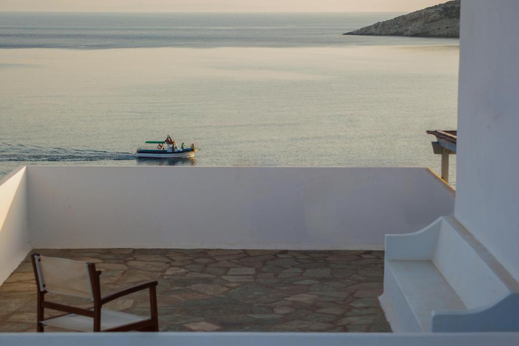 a boat in the water with a chair on a balcony at Oliaros seaside complex in Agios Georgios