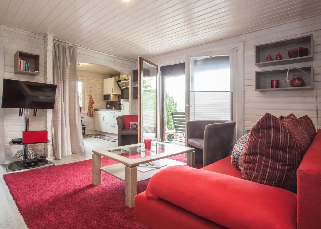 un soggiorno con divano rosso e tavolo di Ferienhaus Auf der Heide 26-S, Winterberg-Niedersfeld a Winterberg