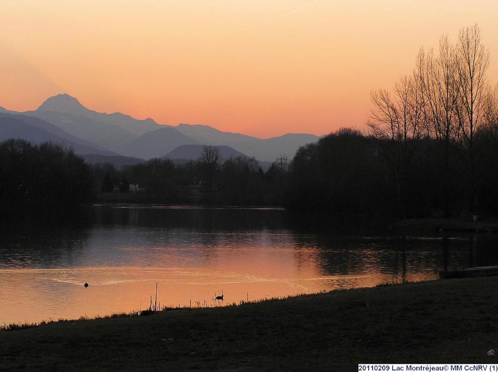 a sunset over a lake with mountains in the background at Les Chalets Montréjeau in Montréjeau