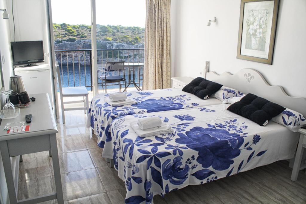 
a hotel room with a bed, table and a window at Hotel Rocamar in Cala Figuera
