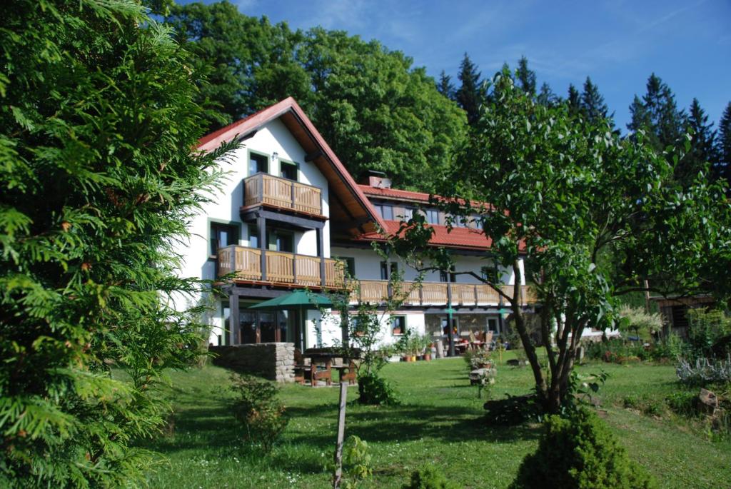Cette grande maison blanche dispose d'un balcon et d'arbres. dans l'établissement Penzion Nadějov, à Kašperské Hory