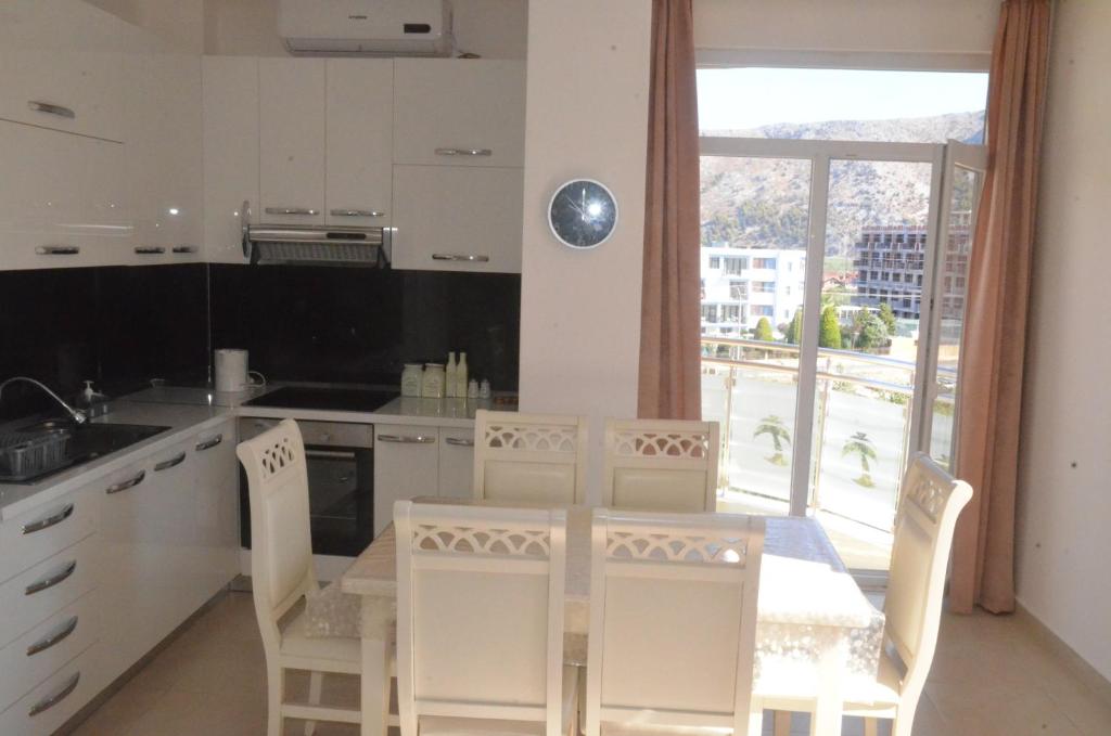 une cuisine avec une table et des chaises ainsi qu'une fenêtre dans l'établissement Everest Apartments Shengjin, à Shëngjin