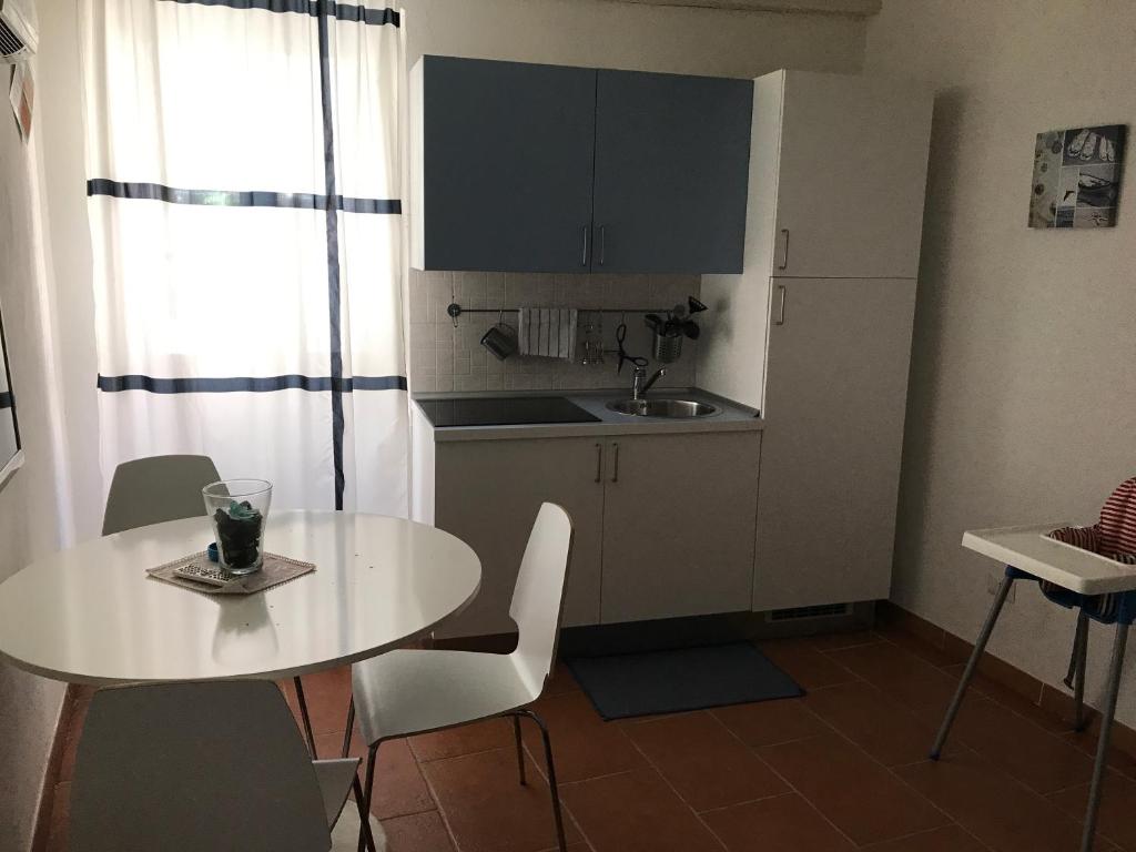 una pequeña cocina con mesa blanca y sillas en H24 Vacanze en Villanova Monteleone