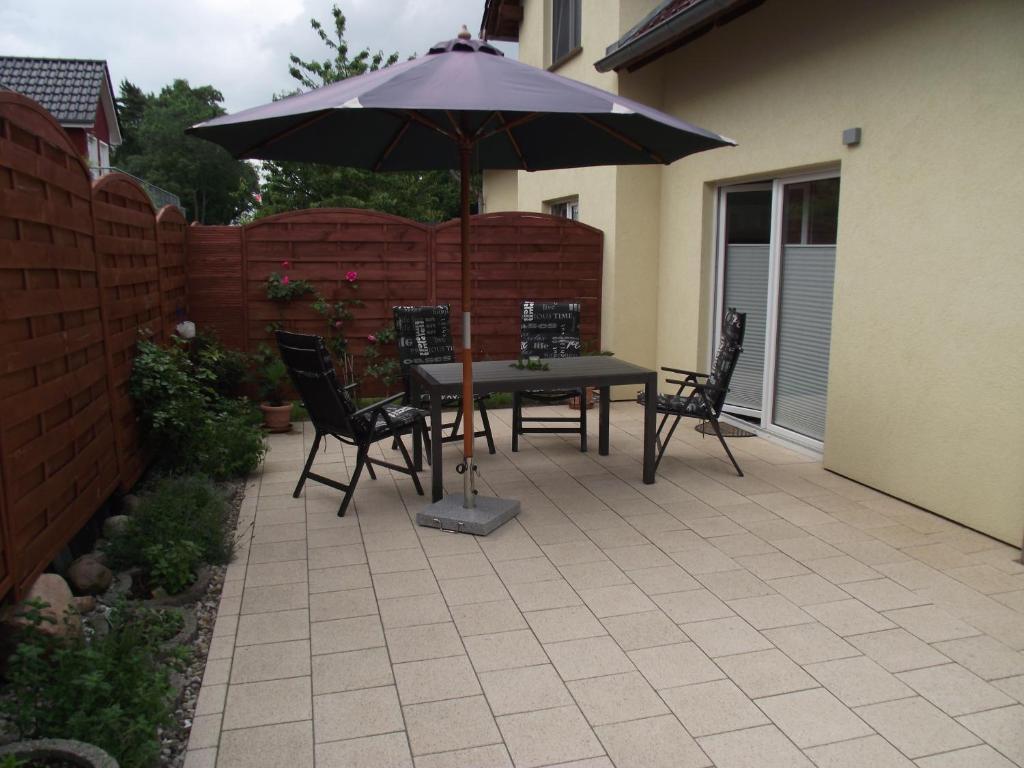 Un patio con una mesa y sillas y una sombrilla. en Ferienwohnung relax, en Ostseebad Koserow