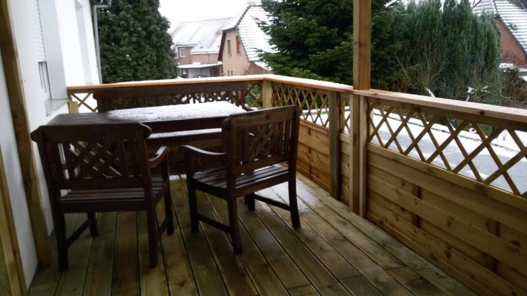 Una terraza de madera con una mesa y dos sillas. en Room Agency Zentrum, en Hannover