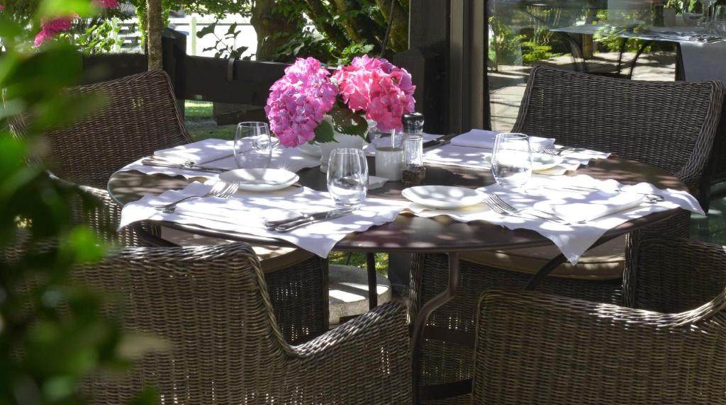 una mesa con vasos y un jarrón de flores. en Logis Hotel Le Relais de Comodoliac, en Saint-Junien