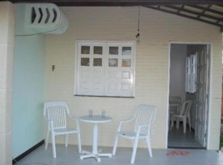 a white table and chairs in a room with a table at CHALÉS ENCANTOS DA ILHA in Barra dos Coqueiros