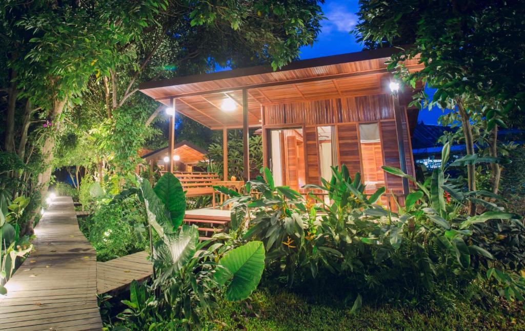 a house in a forest with a wooden walkway at Romyen House in Ban Nong Nam Khan