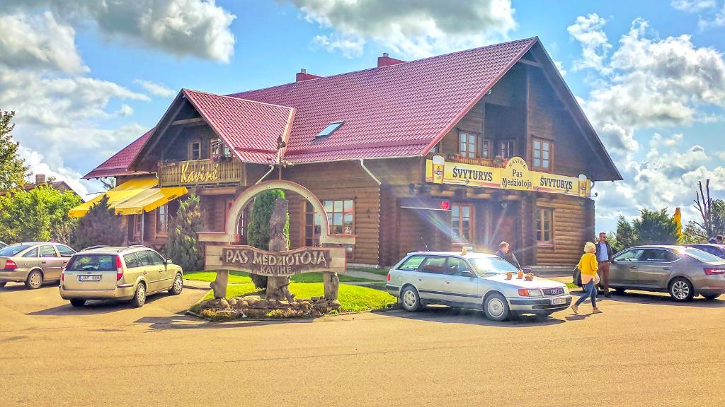 un edificio de madera con un cartel delante en Pas Medžiotoją Motelis, en Kryžkalnis