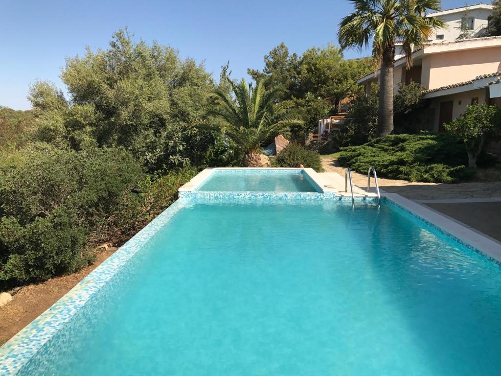 una piscina de agua azul frente a una casa en Le Orchidee Sardegna, en Santa Luria