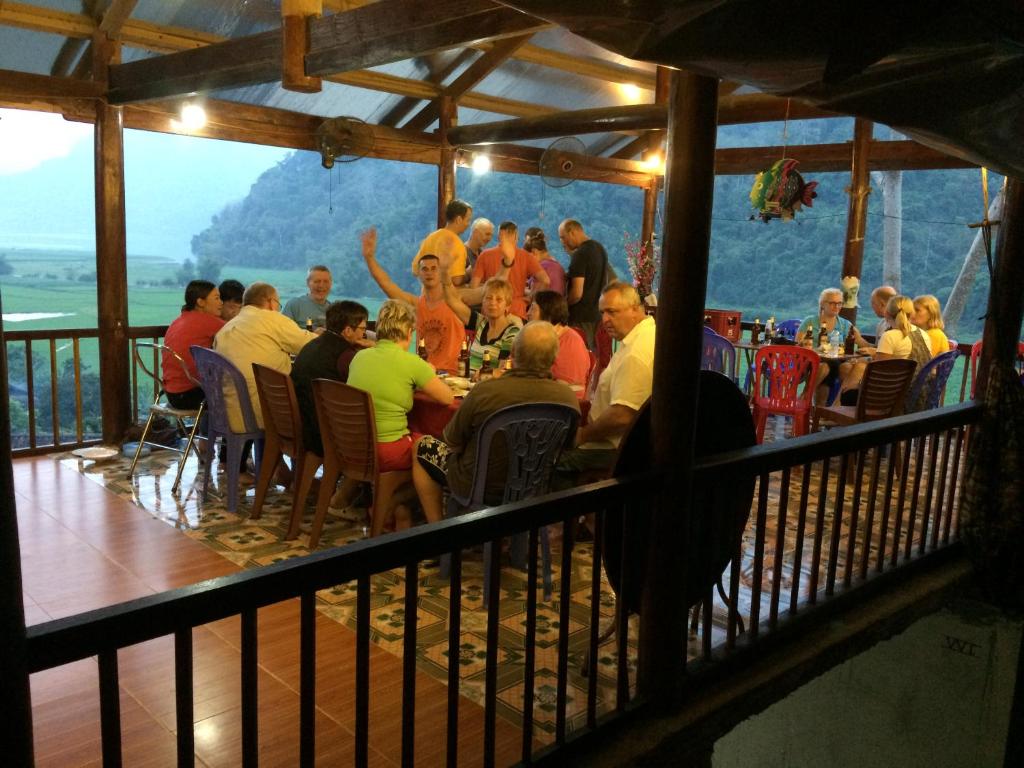 a group of people sitting at tables in a restaurant at Hoàng Nguyên Homestay Ba Be in Ba Be18