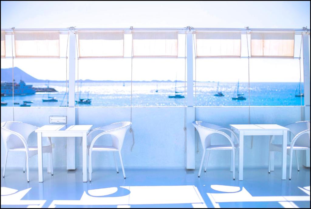 a restaurant with white tables and chairs and windows at AVANTI Lifestyle Hotel - Only Adults in Corralejo