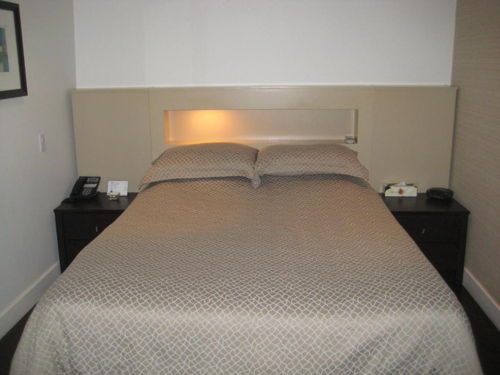 - une chambre avec un grand lit et 2 tables de chevet dans l'établissement Le Relais Lyonnais, à Montréal