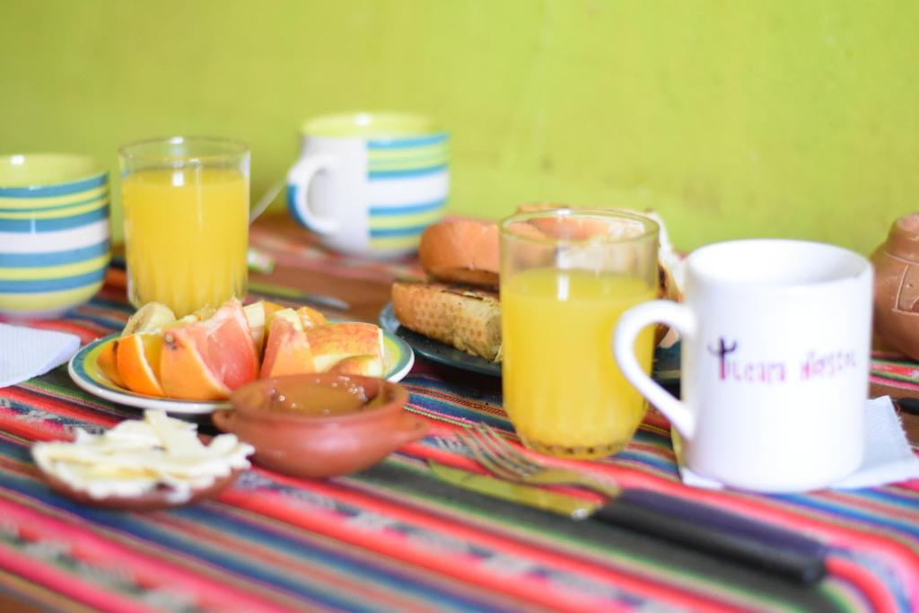 a table with two glasses of orange juice and a plate of food at Tilcara Hostel in Tilcara