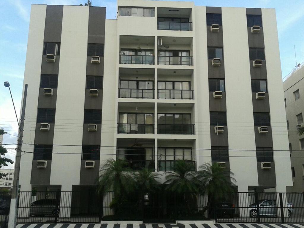 un edificio alto con ventanas y palmeras delante de él en Apartamento Guarujá en Guarujá