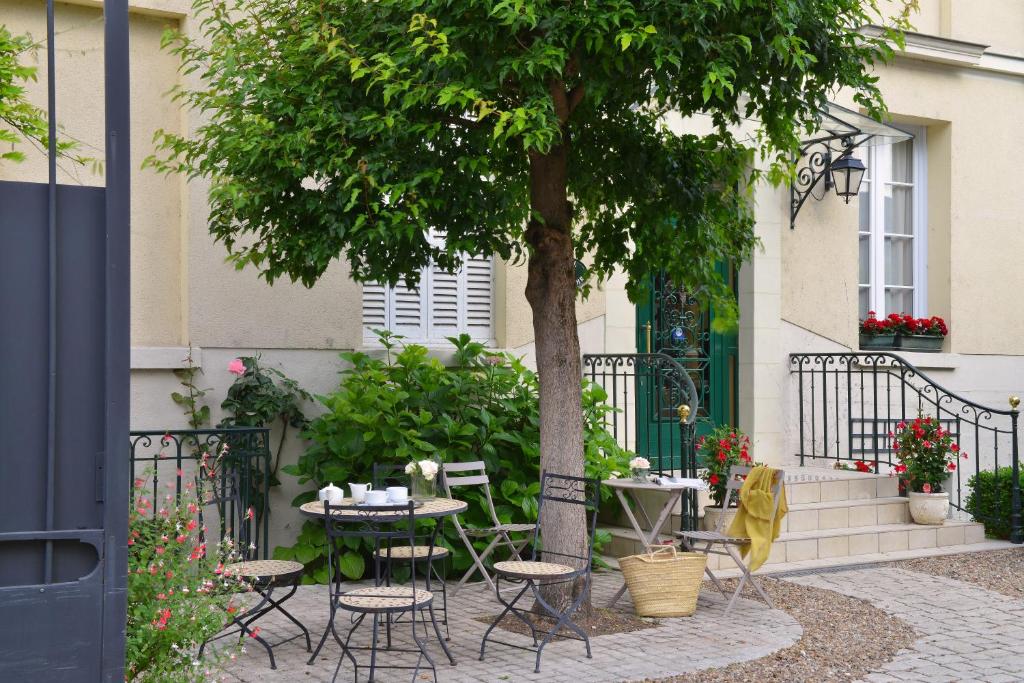 une table et des chaises sous un arbre à côté d'un bâtiment dans l'établissement Hôtel Du Manoir, à Tours