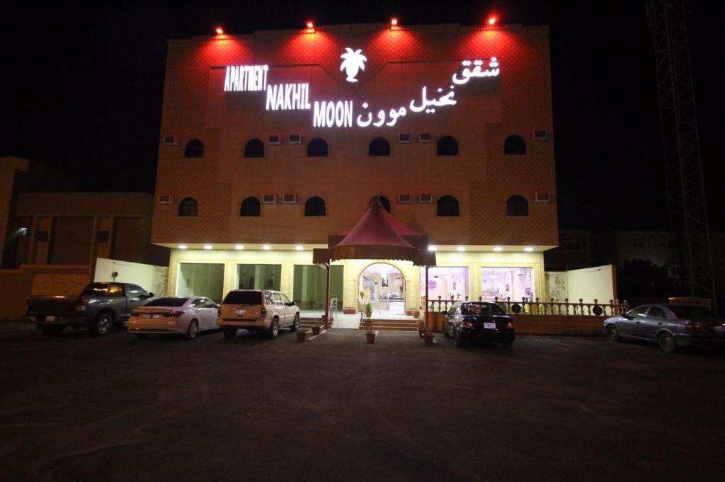 un edificio con coches aparcados delante de él por la noche en Nakhil Moon Serviced Apartments, en Wadi Al Dawasir