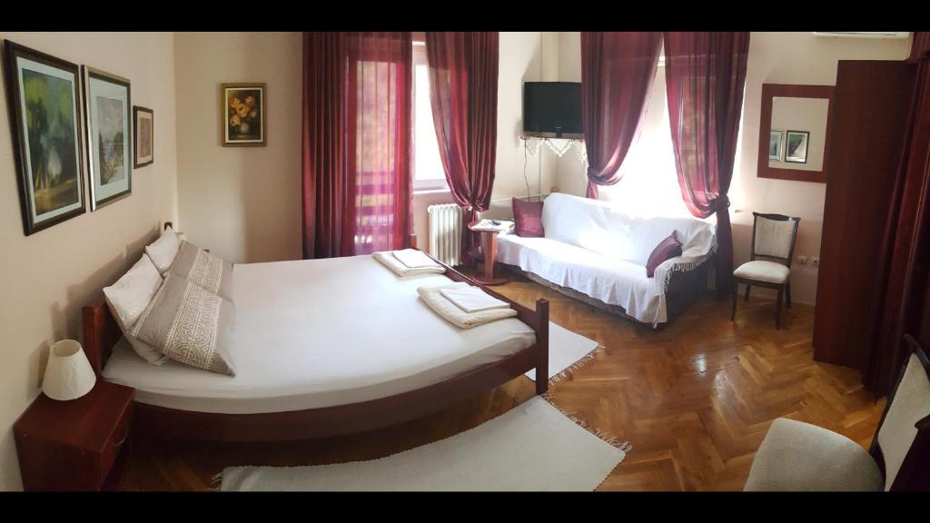 een woonkamer met 2 bedden en een bank bij Guest House Major in Arandjelovac