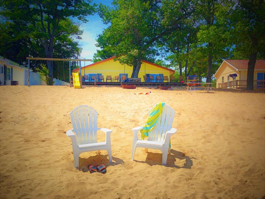 two chairs sitting in the sand on a playground at Gold Coast Family Cottages in Oscoda