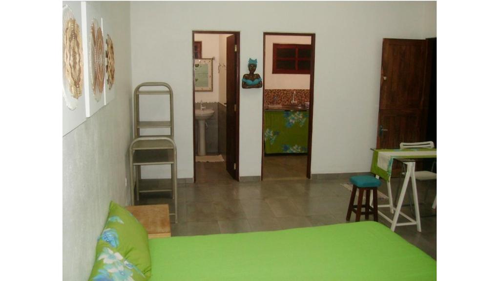 a room with a green bed and a kitchen at Chalé Água de Coco in São Miguel dos Milagres
