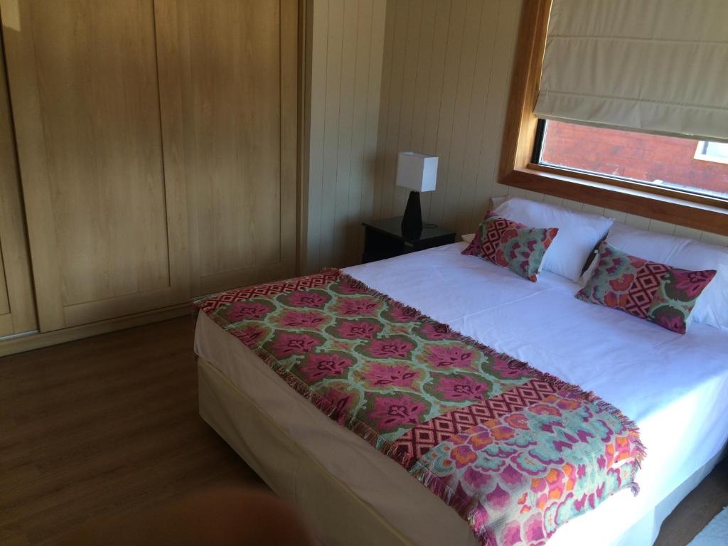 a bedroom with a large bed with a flower blanket at La Cascada Duplex in San Martín de los Andes
