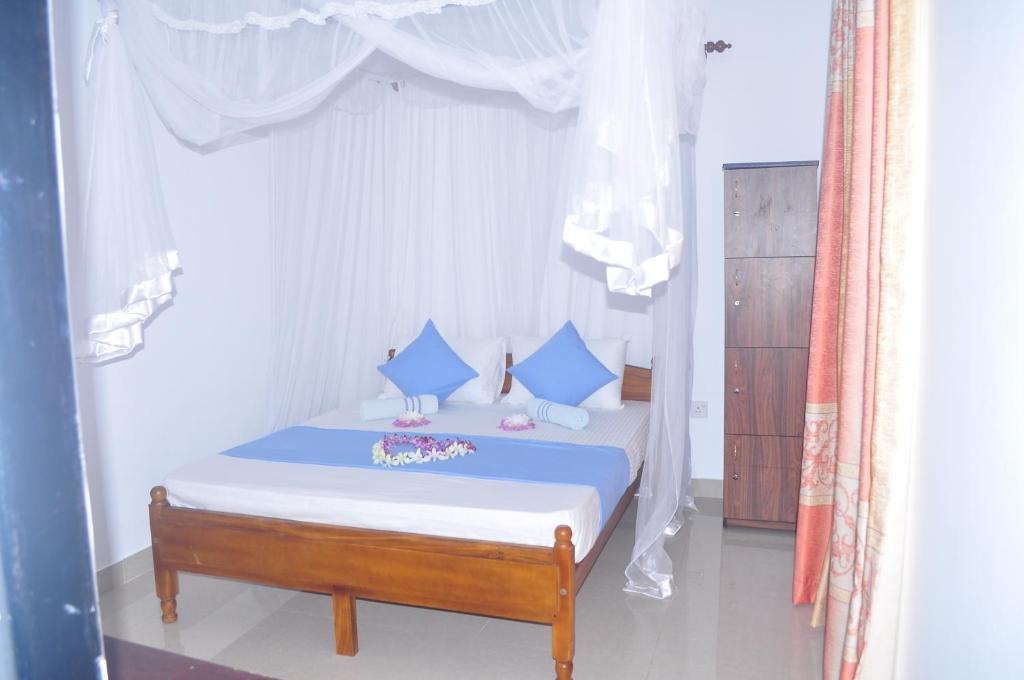 a bedroom with a bed with blue pillows at Bentota Orchid House in Bentota
