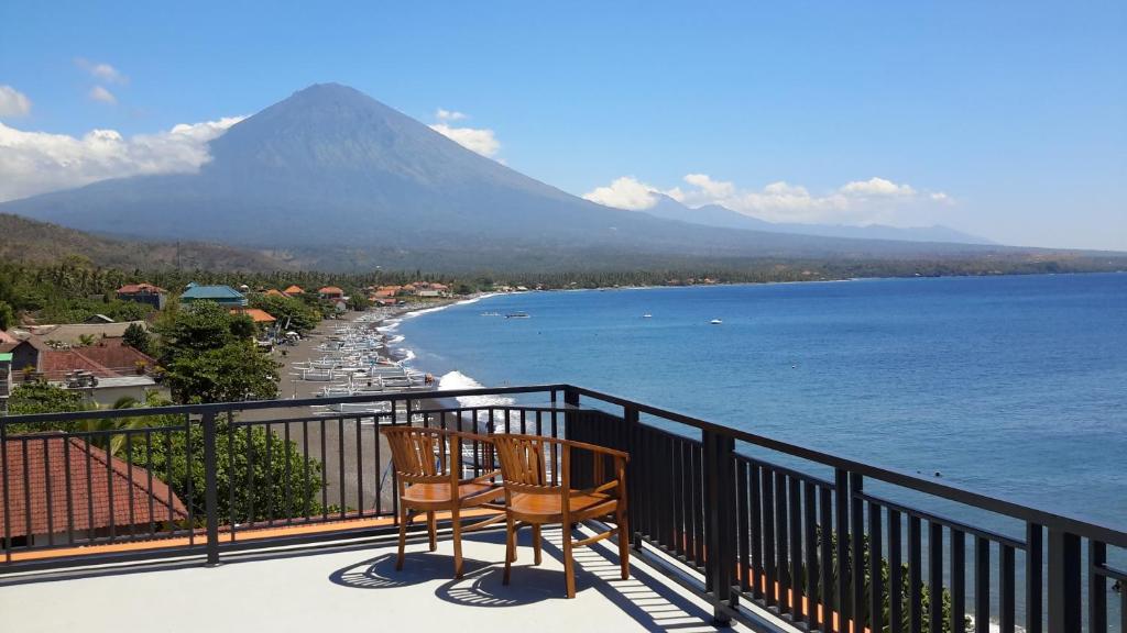 a balcony with two chairs and a view of a mountain at Amed Beach Villa in Amed