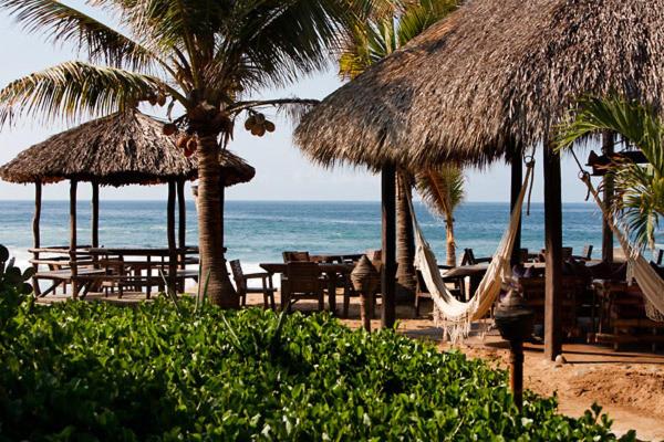 a beach with chairs and umbrellas and the ocean at El Alquimista Yoga Spa in Zipolite