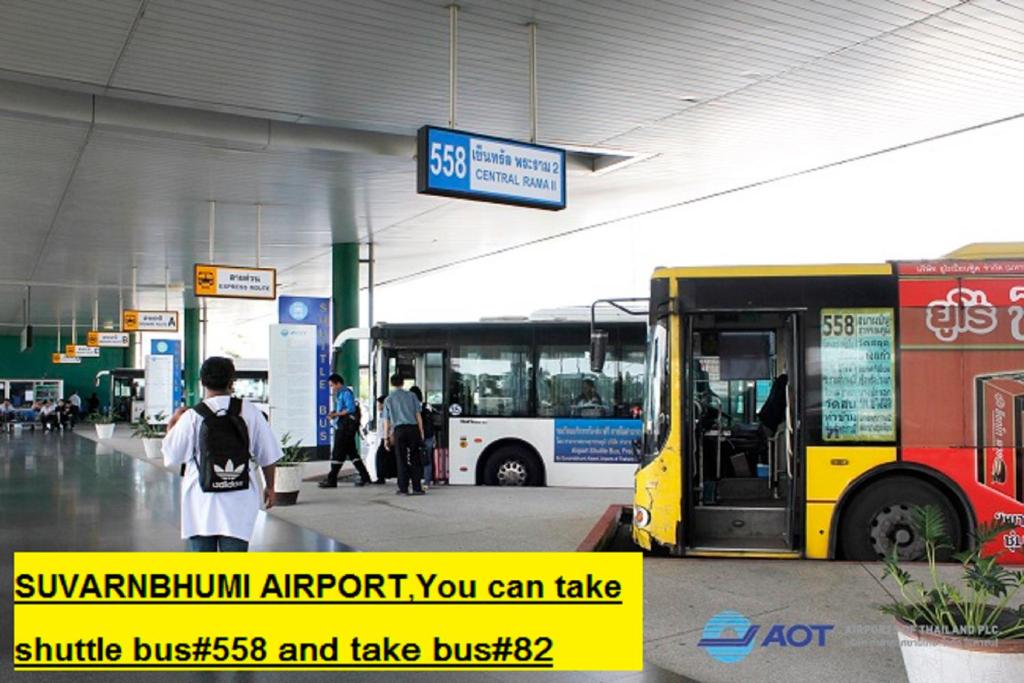 un autobús amarillo y blanco estacionado en una estación de autobuses en Anurak Guesthouse, en Bangkok