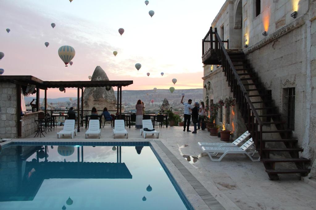 eine Gruppe von Heißluftballons, die über einen Pool fliegen in der Unterkunft Shoestring Cave House in Goreme