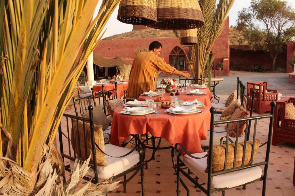 a man is standing at a table in a restaurant at Hotel De Charme Les 3 Chameaux 4 étoiles in Mirleft