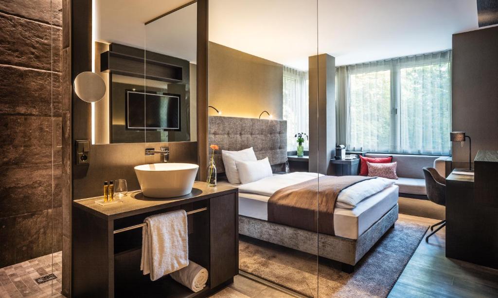 Schlafzimmer mit einem Bett, einem Waschbecken und einem Spiegel in der Unterkunft SAKS Urban Design Hotel Frankfurt in Frankfurt am Main