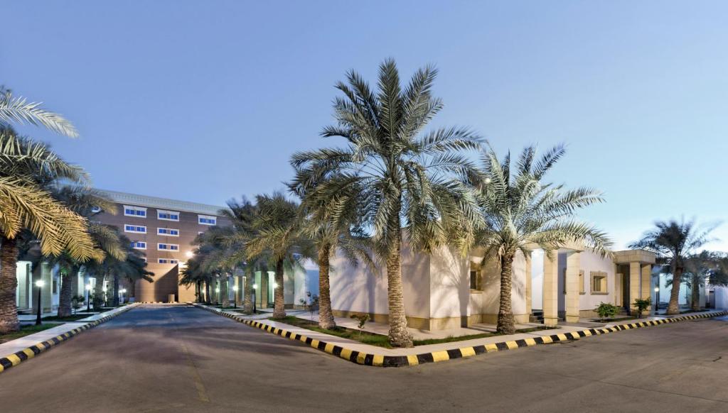 una calle con palmeras frente a un edificio en Al Gosaibi Hotel - Villa, en Al Khobar
