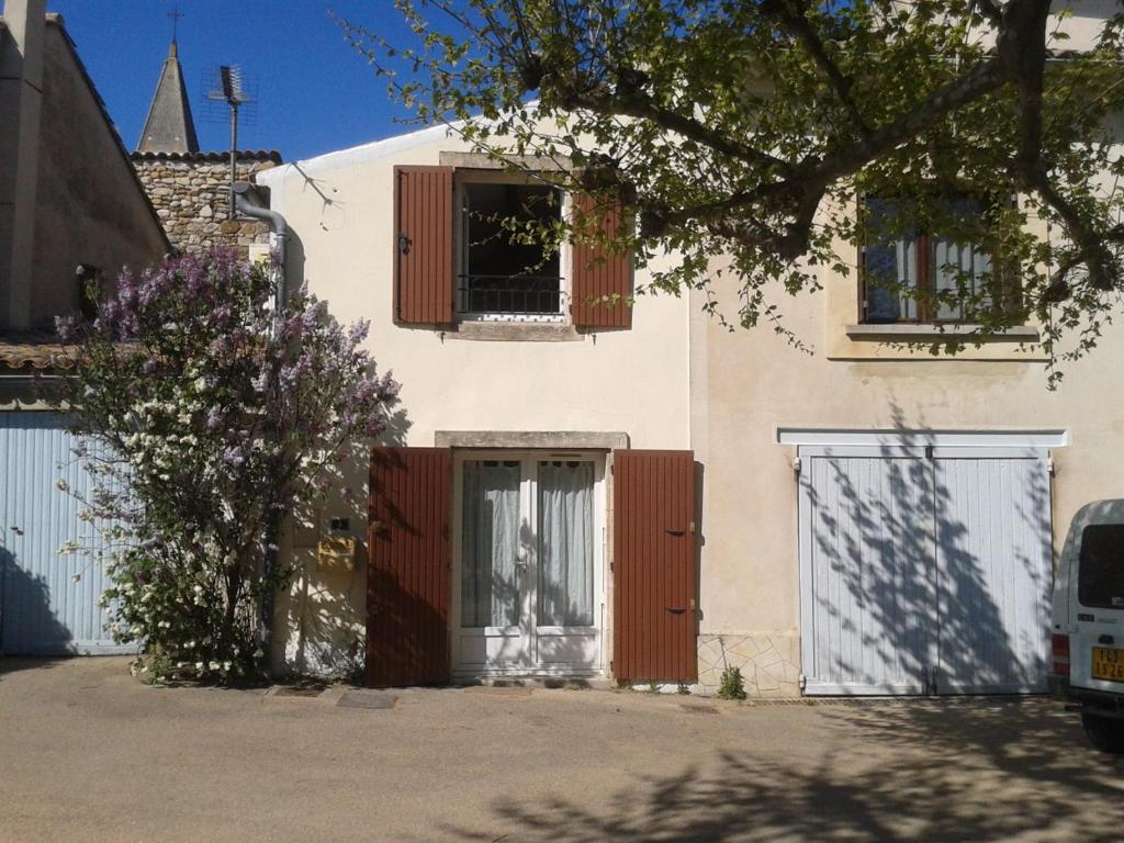 a white house with red doors and a fence at Maison Sous les Platanes in Saint-Pantaléon-les-Vignes