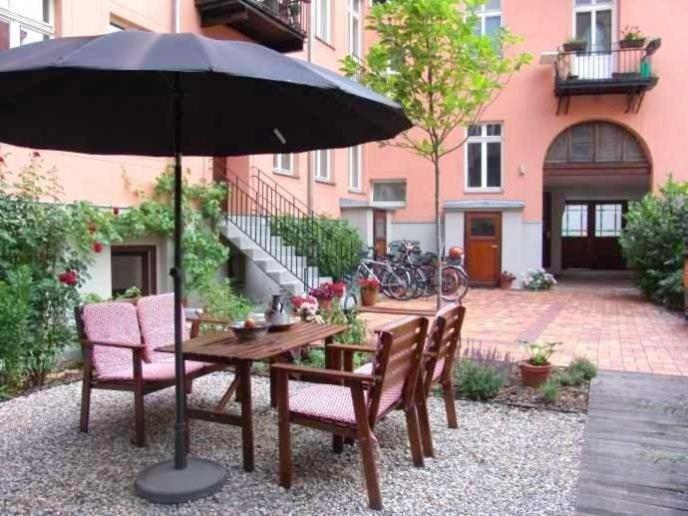une table en bois avec des chaises et un parasol dans l'établissement Berlin Apartments Mitte, à Berlin