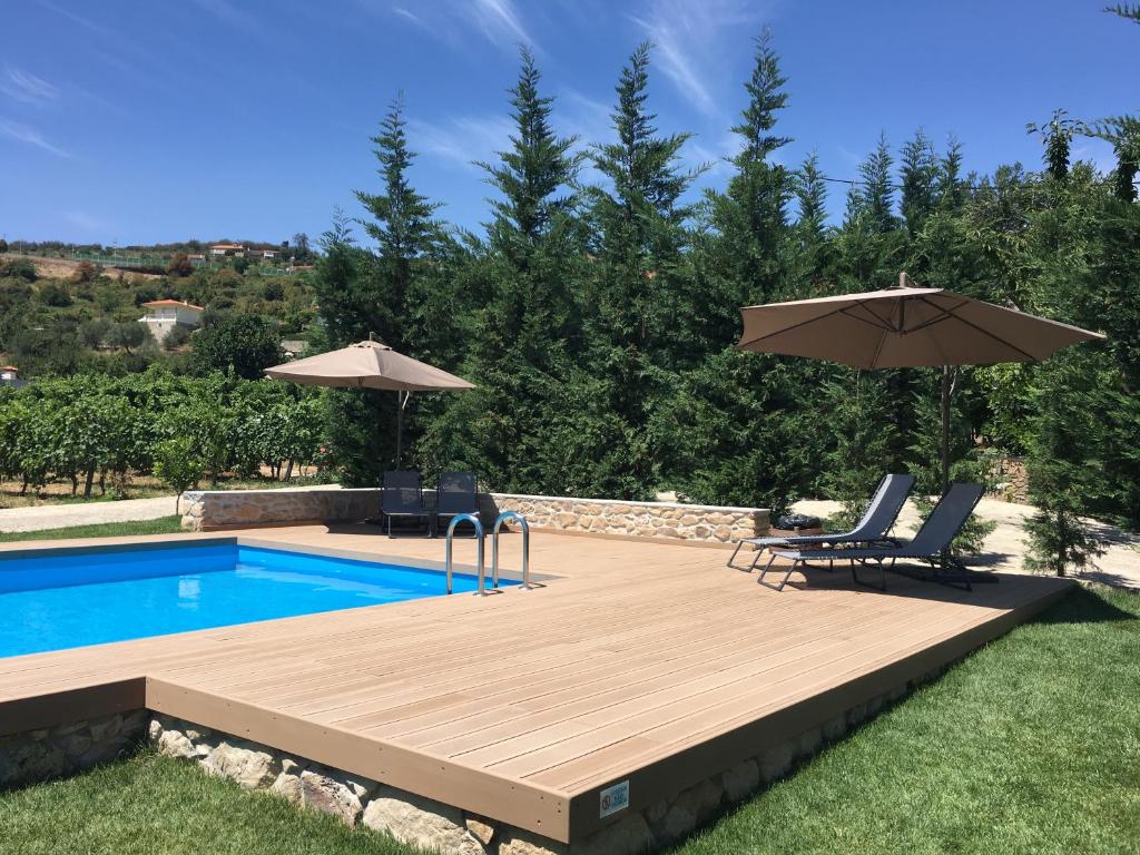 a swimming pool with two chairs and an umbrella at Quinta Do Acipreste (Antiga Quinta Da Torre) in Lamego