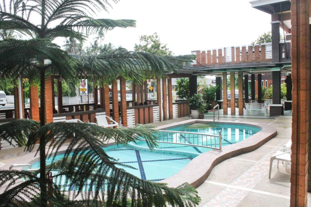 a swimming pool with a palm tree and a building at Myvilla Langkawi Hotel in Pantai Cenang