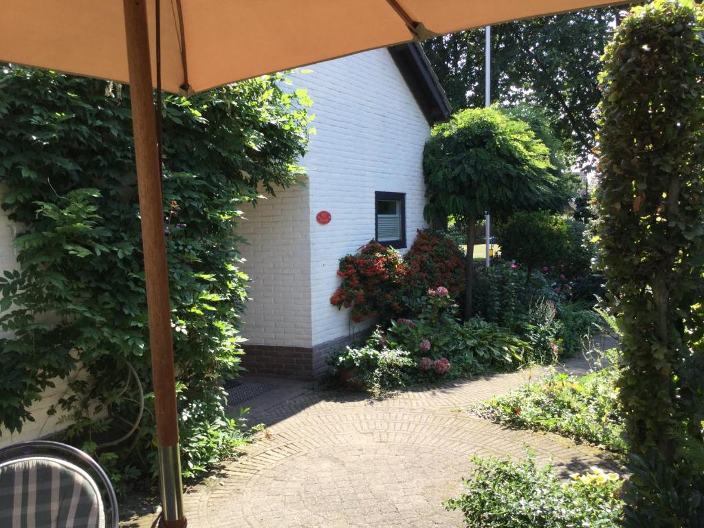 an outside view of a house with flowers and an umbrella at B&B Bosrand in Groesbeek