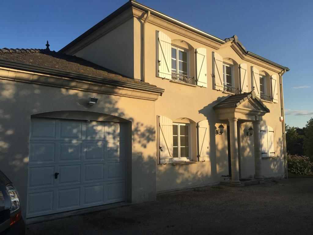 uma grande casa branca com uma porta de garagem em Gîte "Le Millésime 61" em Flavigny