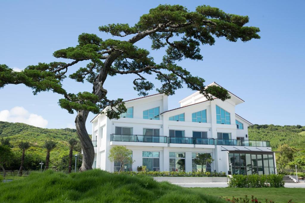 un edificio blanco con un árbol delante en 墾丁椰林 海灘文旅 en Eluan