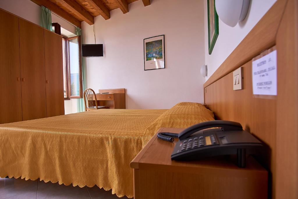 una camera d'albergo con telefono su un letto di Hotel Tiziana Garnì a Gargnano