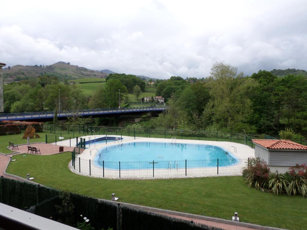 a swimming pool in a park with a train in the background at Apartamento Jardines del Sella in Cangas de Onís