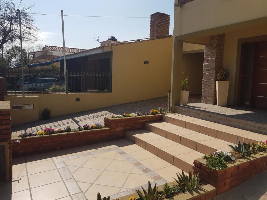 una casa con escaleras y flores en un patio en LOS ANDES Departamentos en Villa Carlos Paz