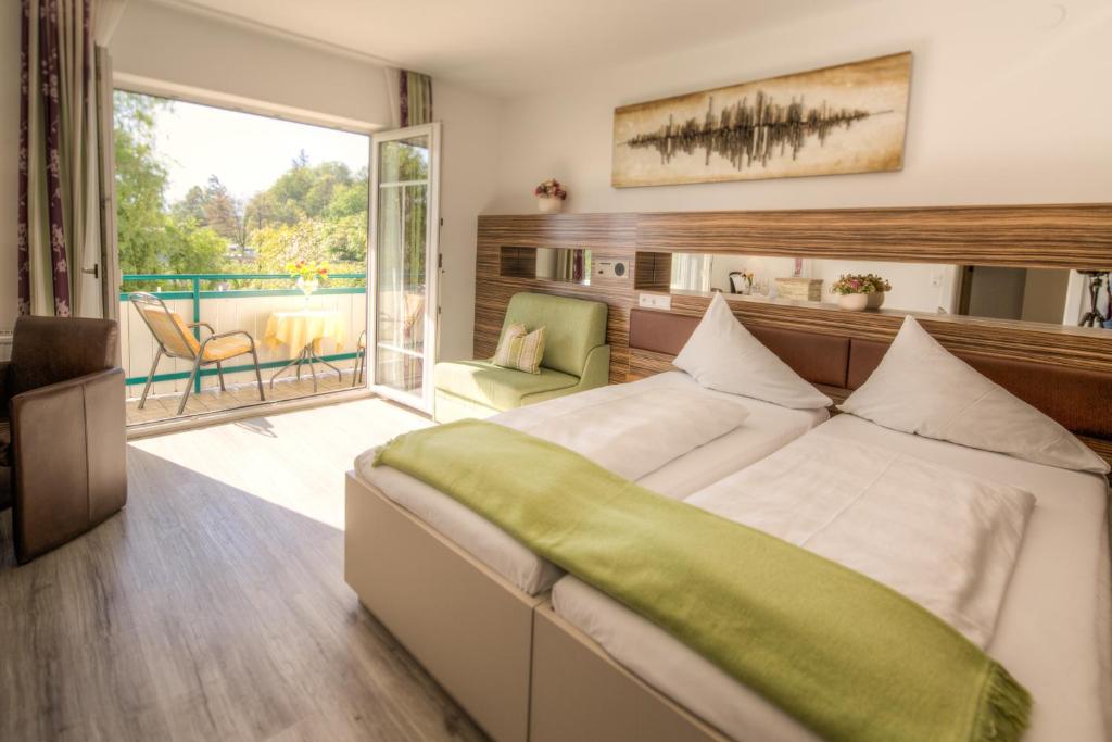 a bedroom with a large bed and a balcony at Hotel Weidenhof in Klagenfurt